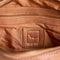 up close of brown leather barrel purse with long strap zipper pulls and various zipper compartments