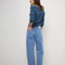 back view of model wearing medium blue denim with a relaxed fit and slight cropped hem