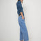 side view of model wearing medium blue denim with a relaxed fit and slight cropped hem