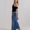 side view of model wearing light indigo pull on jeans with elastic tie waist and patch front pockets