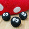 set of three black mini sprites with big white eyes on a table