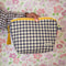 model holding navy and cream gingham quilted pouch with yellow print trim
