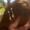 model wearing set of two dark green marbled setting clips with dainty white flower and gold accent