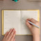 model writing in pale yellow journal with matching elastic closure