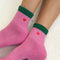 up close of model wearing pink crew socks with green trim and red embroidered heart