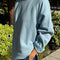side view of model wearing light blue relaxed fit raglan sweatshirt