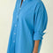 side view of model wearing oversized lake blue button down top