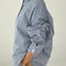 side view of model wearing blue and white vertical pinstripe denim button up shirt