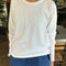 model wearing relaxed fit white long sleeve top with slight distressing around the collar