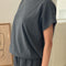side view of model wearing coal tee with slight cap sleeves, relaxed fit, and banded bottom