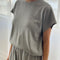 model wearing heather grey tee with slight cap sleeves, relaxed fit, and banded bottom