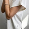side view of model wearing white relaxed tee with muscle tee sleeves and side vents at the hem