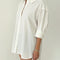 side view of model wearing white relaxed fit button front shirt with side vents and collar
