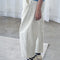 side view of model wearing white relaxed fit pull on pants with side pockets and side panels