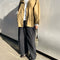 model wearing relaxed fit brown/tan waxed cotton jacket with side pockets, high collar and side vents with black pants