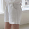 side view of model wearing white cotton shorts with side pockets