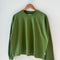avocado colored long sleeve tee with elastic wristbands on a hanger
