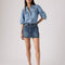 model wearing medium blue mini denim skirt with pin tucked denim blouse
