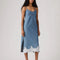 model wearing light denim slip dress with side slits and scalloped lace hem
