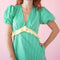 up close of model wearing green puff sleeve v-neck midi dress with  pale yellow ruffle under the bust