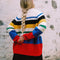 back view of model wearing primary color mockneck tunic with white, blue, black, yellow, green, blue and red different sized stripes