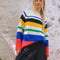 model wearing primary color mockneck tunic with white, blue, black, yellow, green, blue and red different sized stripes