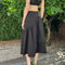 back view of model wearing black twill midi skirt with wavey hem detail