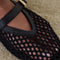 up close of model wearing black open woven ballet flats with strap and gold buckle