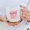 model holding white ceramic mug with hot pink 'CATS AGAINST CATCALLS' with a tiger on it