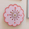 side view of light pink retro daisy shaped clock with mauve trim