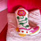 white boot shaped throw pillow with pink and yellow flower design on chair