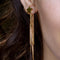 up close of model wearing gold star earrings with gold chains coming from the back