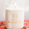 lit soy candle with pale yellow and white vertical stripe label and says 'smells like a bookstore' across the front