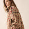 side view of model wearing tan fleece half zip sweatshirt with red floral print and black piping on the arms and zipper