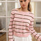 model wearing light pink cardigan with thin brown and white striped