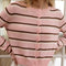 up close of model wearing light pink cardigan with thin brown and white striped