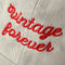 up close of tan dad hat with red embroidered 'vintage forever'