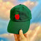 model holding green dad hat with red tomato design
