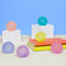 set of 6 mini memory gel stress balls in teal, yellow, pink, purple, misty blue, and peach on a desk