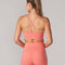 back view of model wearing bright coral sports bra