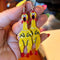 model holding yellow rubber chicken dangle earrings