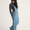 side view of model wearing stonewash relaxed fit overalls with multiple pockets and 'carpenter' type style