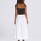 backview of model wearing white flowy midi skirt with black tank and vans sneakers