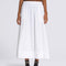 model wearing white flowy midi skirt with black tank and vans sneakers