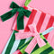 up close of velvet bows on set of two striped stockings: dark green and lime green top with pink and red striped bottom and pink and red stripe top and dark green and baby blue striped bottom
