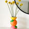 Stacked citrus vase on mantle with yellow round flowers