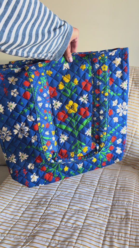 model putting items into blue folk floral tote bag