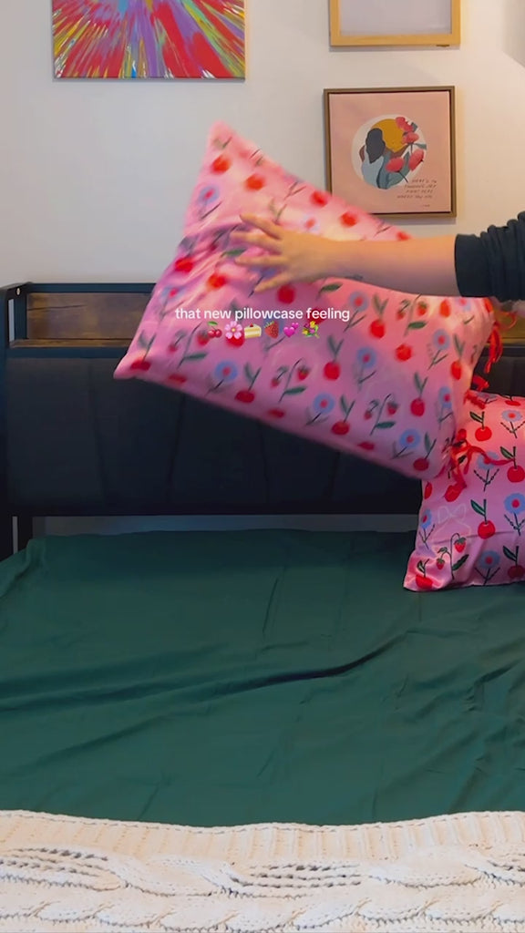 model decorating with set of 2 pink pillowcases with red 'magnifique' and 'romantique' with red side tie closure and red squiggle border