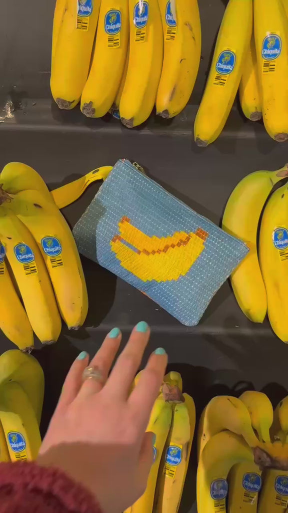 model picking up bananas with small rattan pouch with banana design and zipper top on the display