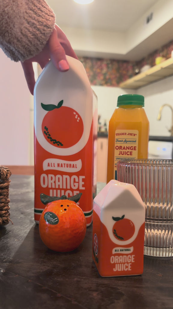 model setting up a table with orange juice vase and orange juice salt and pepper shakers